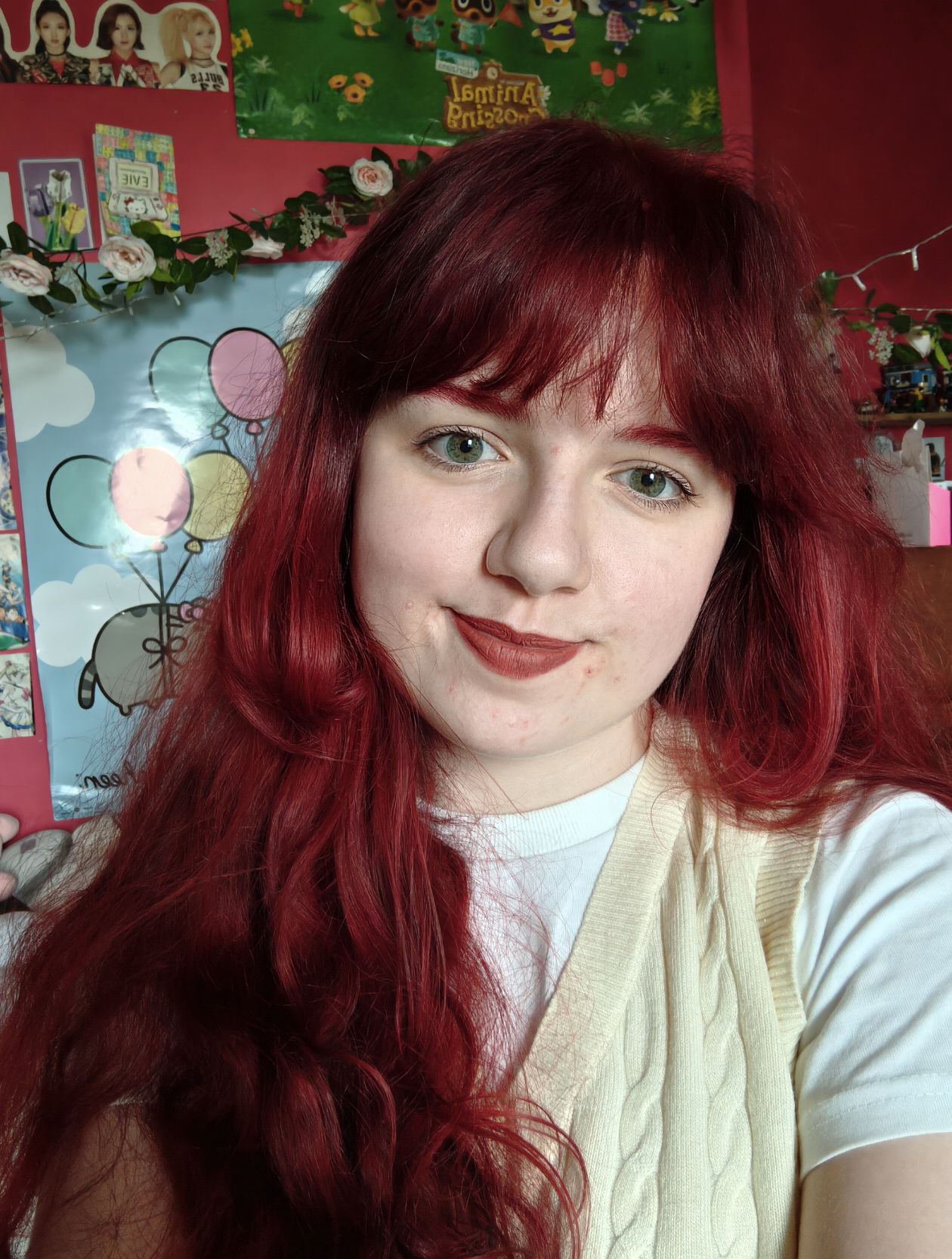A photo of me from shoulders up, a young white woman with red hair and a yellow sweater vest.